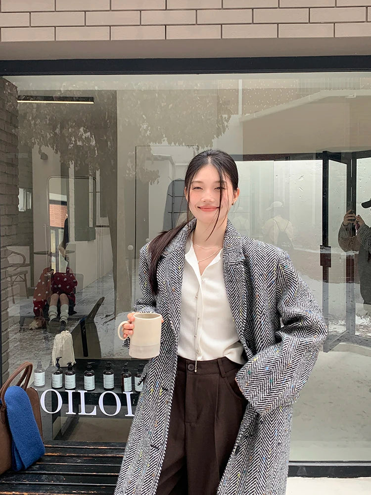 Model wearing a solid plaid minimalist woolen coat in a city street setting