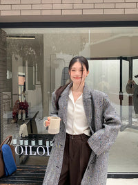 Model wearing a solid plaid minimalist woolen coat in a city street setting