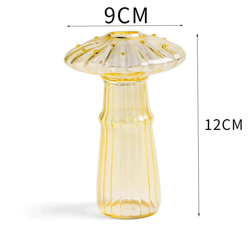 Clear glass mushroom-shaped vase with hydroponic plant and flowers on a minimalist home table


