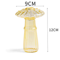 Clear glass mushroom-shaped vase with hydroponic plant and flowers on a minimalist home table

