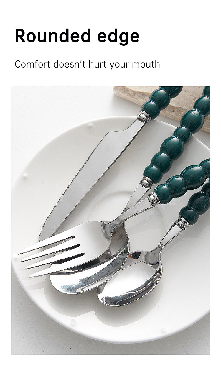 Set of 4 high-end stainless steel cutlery with colorful pearl handles on an elegant dining table