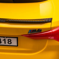 Yellow BMW M4 12V electric ride-on car for kids, featuring authentic design with working headlights, MP3 player, and forward/reverse motion. Comes with adjustable seat and steering wheel, providing a realistic driving experience for children aged 3-6