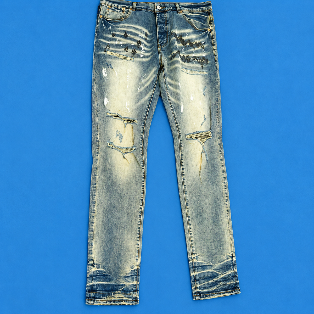 Distressed light-wash blue jeans with heavy fading, whiskering, and ripped details on the thighs and legs, laid flat against a solid blue background.