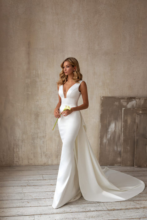 Elegant sleeveless wedding dress with deep V-neckline, lace embroidery, and a long flowing tail for a breathtaking bridal look.

