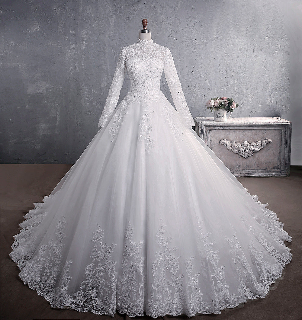 A white lace wedding dress with a stand-up collar, long sleeves, and a flowing large tail, designed for a classic and elegant bridal look.

