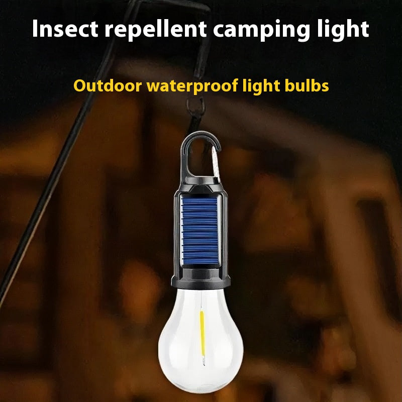 Solar-powered camping lantern with tungsten bulb hanging in a tent outdoors

