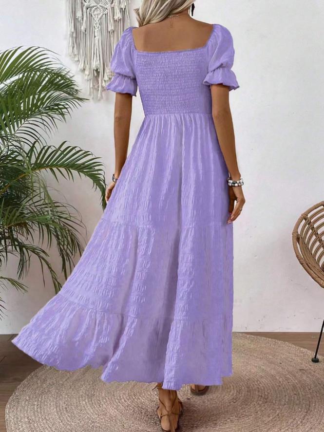 A woman wearing a lavender purple tiered maxi dress with puff sleeves and a smocked bodice, shown from the back in a styled indoor setting.