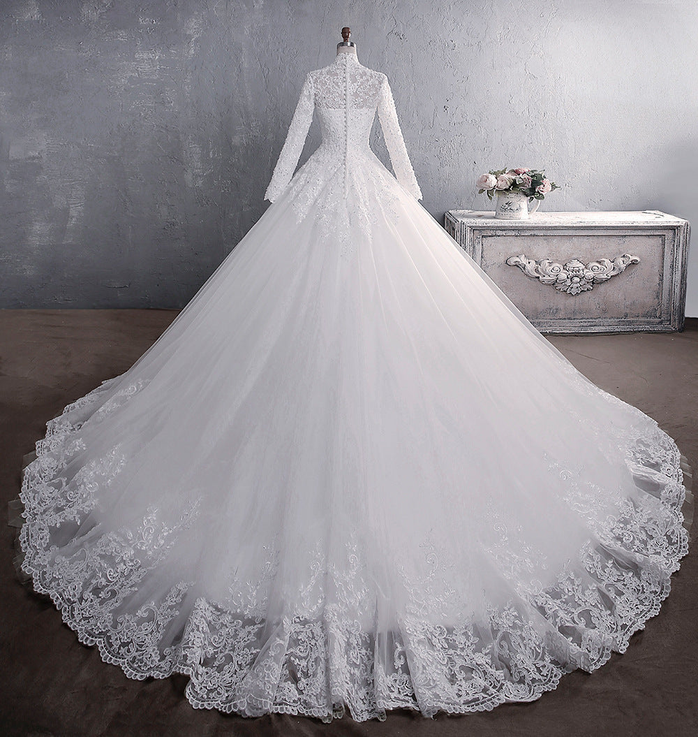 A white lace wedding dress with a stand-up collar, long sleeves, and a flowing large tail, designed for a classic and elegant bridal look.

