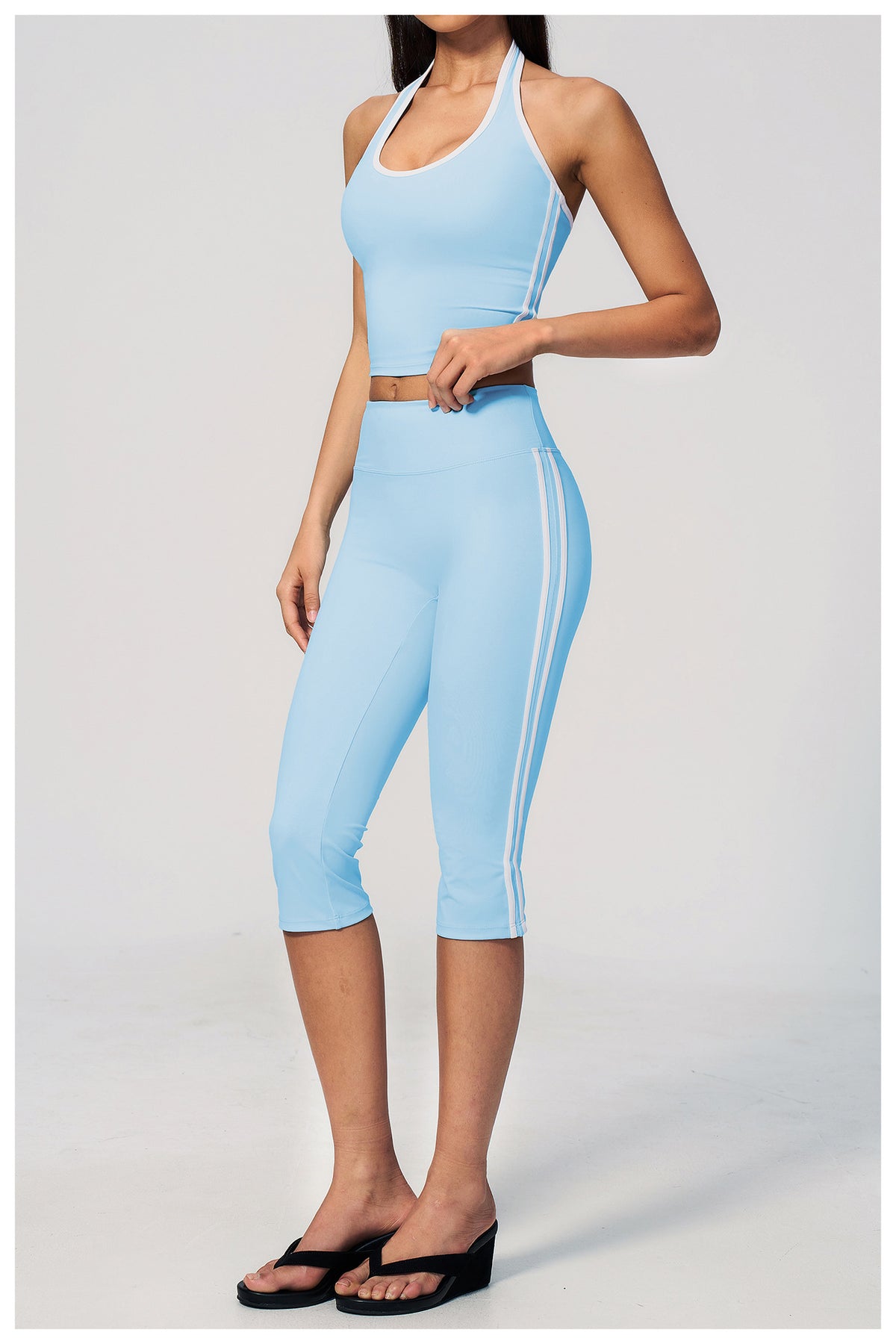 Light blue athletic outfit with a halter top and capri leggings on a white background