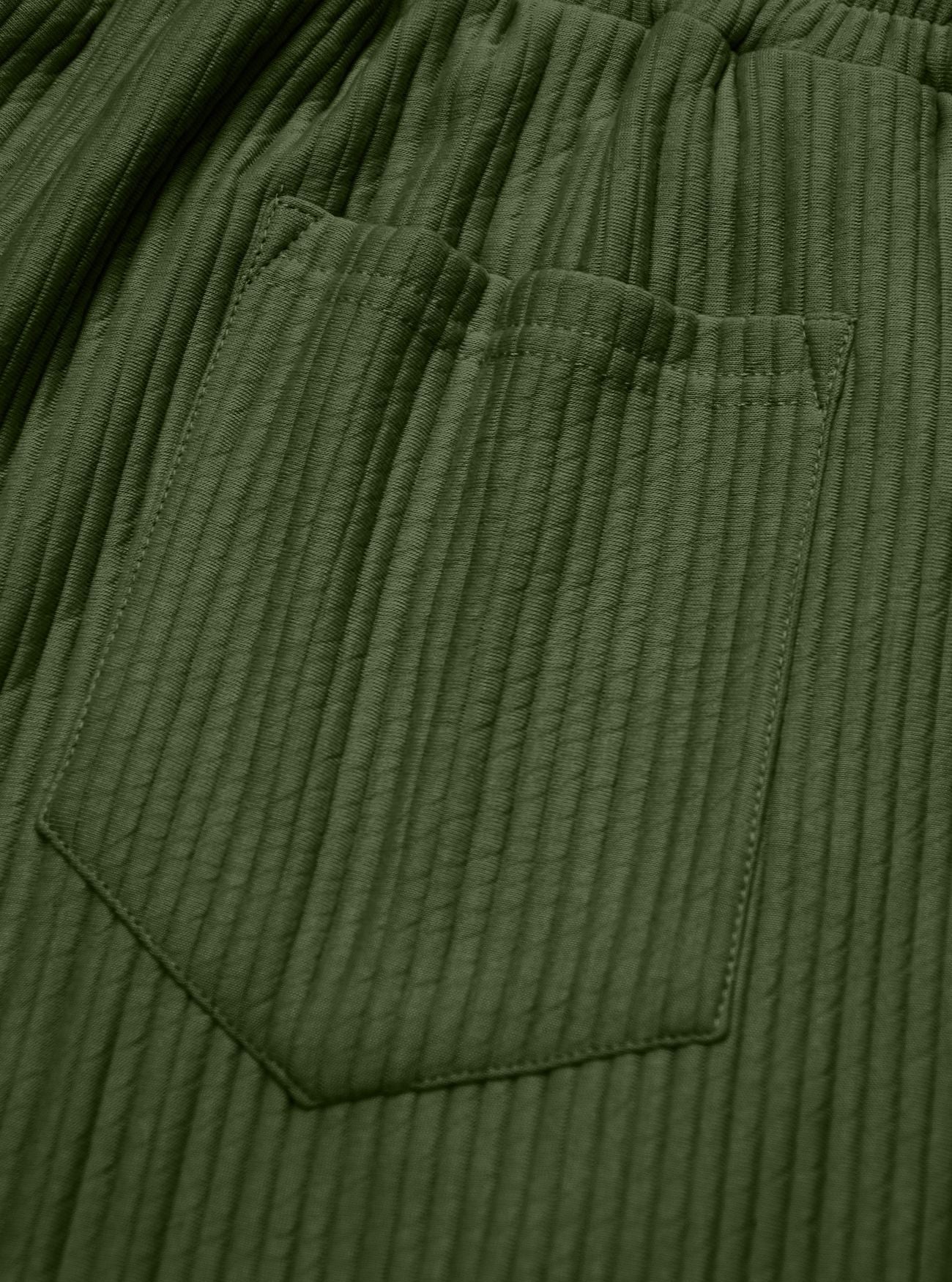 Close-up of olive green ribbed fabric with a stitched pocket and elastic waistband.