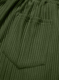 Close-up of olive green ribbed fabric with a stitched pocket and elastic waistband.