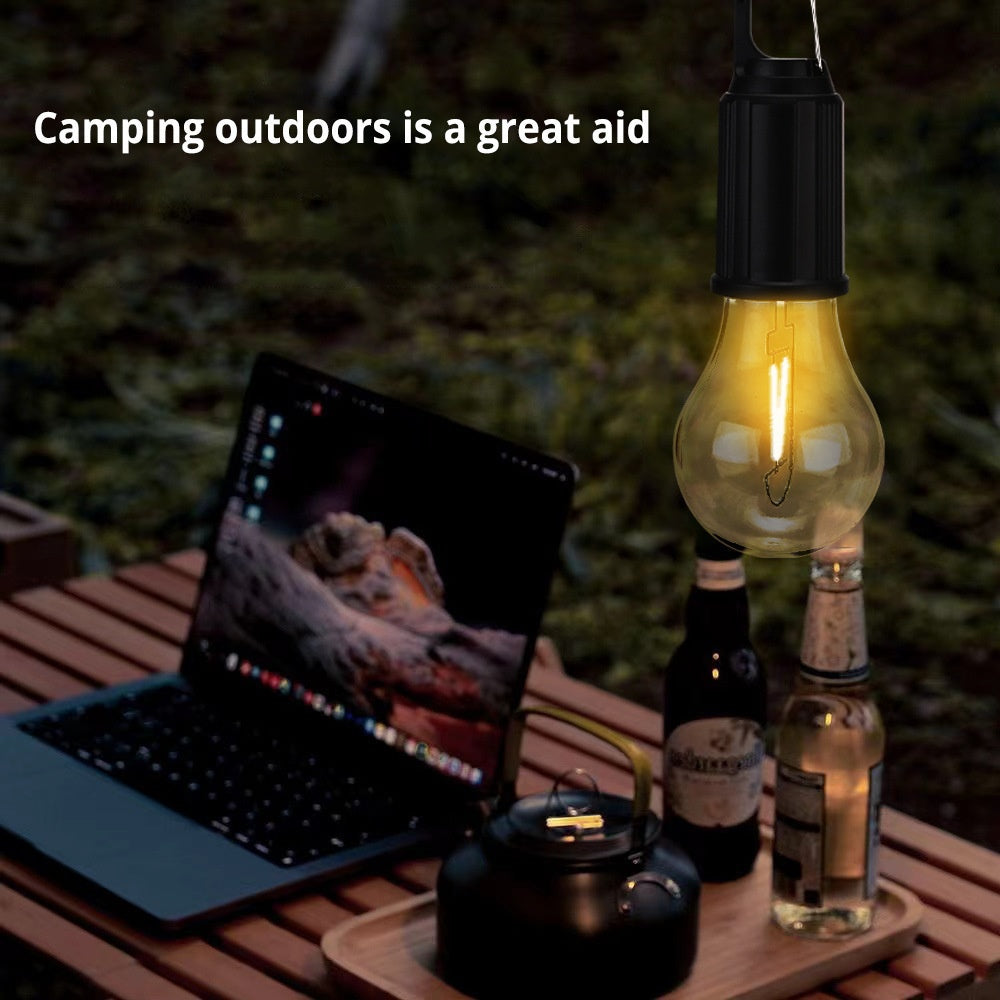 Solar-powered camping lantern with tungsten bulb hanging in a tent outdoors

