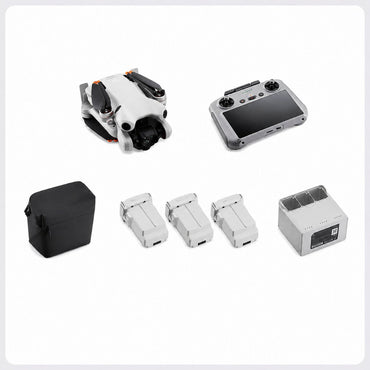 A drone kit laid out on a light gray background, including a folded white drone with black and orange accents, a gray remote controller with a black screen, a black carrying case, four white battery packs, and a gray charging box.