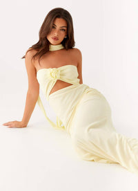 Woman wearing a strapless yellow dress with a floral detail on a white background