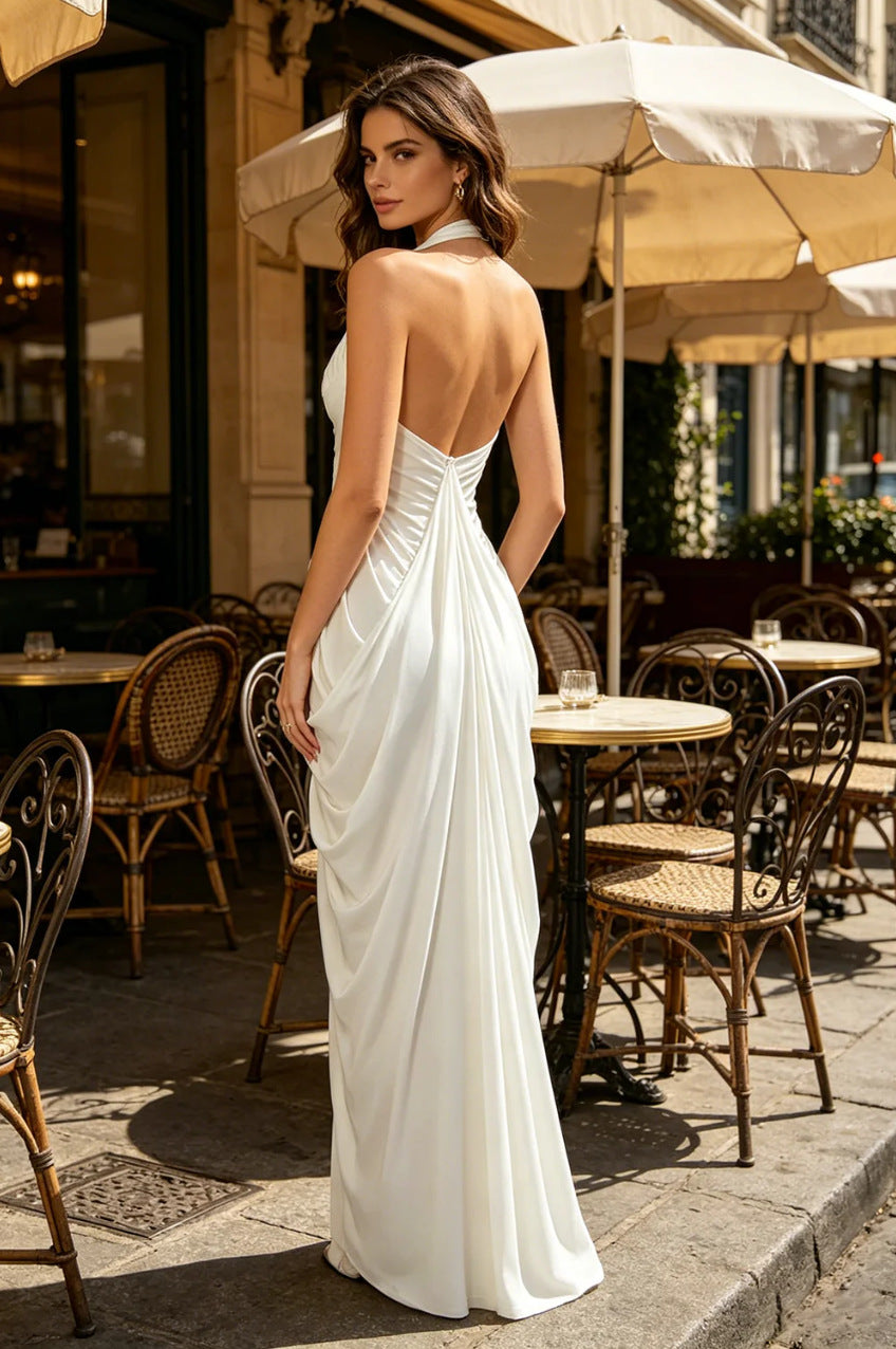 Woman in a white dress standing outdoors with tables and chairs in the background