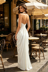 Woman in a white dress standing outdoors with tables and chairs in the background