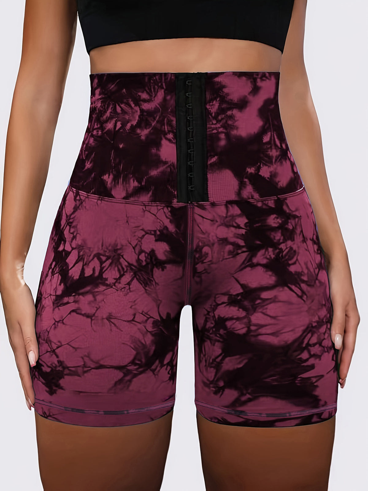 High-waisted athletic shorts with a black lace-up front and a dark purple and black tie-dye pattern, shown on a model.