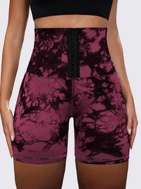 High-waisted athletic shorts with a black lace-up front and a dark purple and black tie-dye pattern, shown on a model.