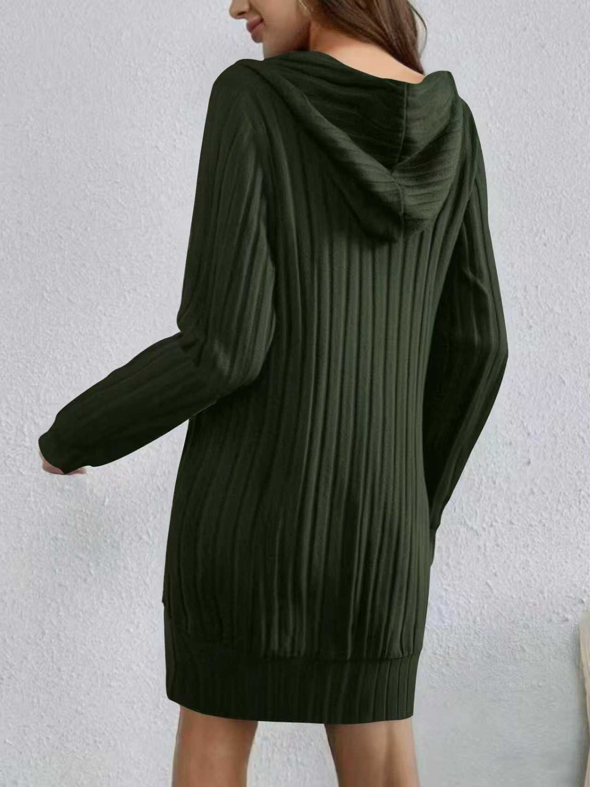 Green ribbed sweater dress worn by a person on a light gray background