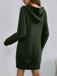 Green ribbed sweater dress worn by a person on a light gray background