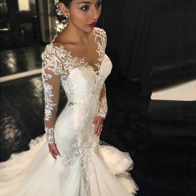 A trailing white lace wedding dress with a slim fit and elegant design, featuring intricate lace details for a timeless bridal look.

