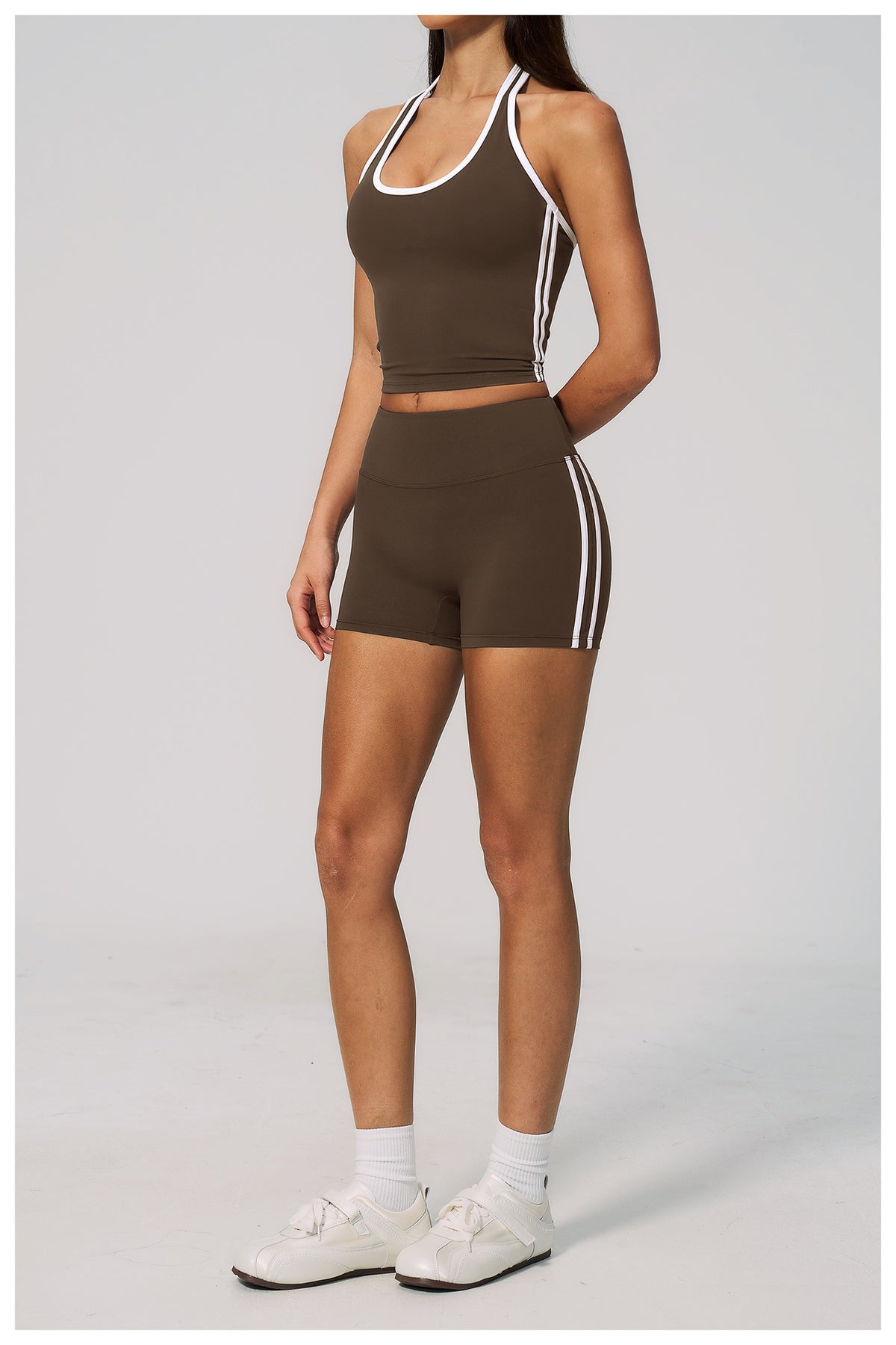 Person wearing a brown athletic outfit with white stripes on a light gray background