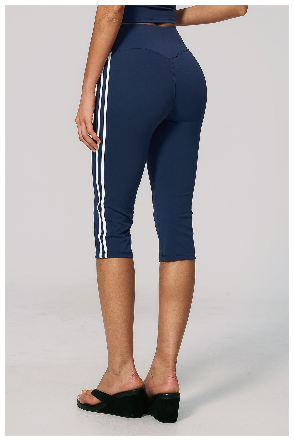 Navy blue capri leggings with white stripes on a plain background