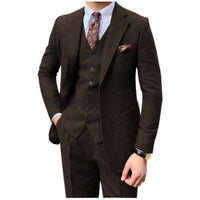 A men's three-piece brown tweed suit including a jacket, vest, and trousers, styled with a white dress shirt, a brown paisley tie, and a matching pocket square on a white background.